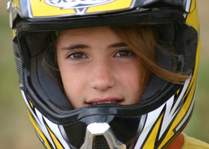 Une fille porte un casque car elle est en train de faire l'activité sports mécaniques au Haras de Val en Pré 100% sports mécaniques