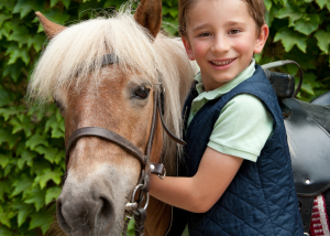 Un enfant avec son poney attitré pendant son séjour au Poney Club de Val-en-Pré équitation au Far West