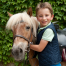 Un enfant avec son poney attitré pendant son séjour au Poney Club de Val-en-Pré équitation au Far West